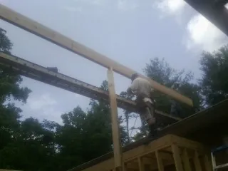 Carpenter setting a ridge beam over a new addition frame — Ice Dam Removal by Roofing Brothers in Vanleer