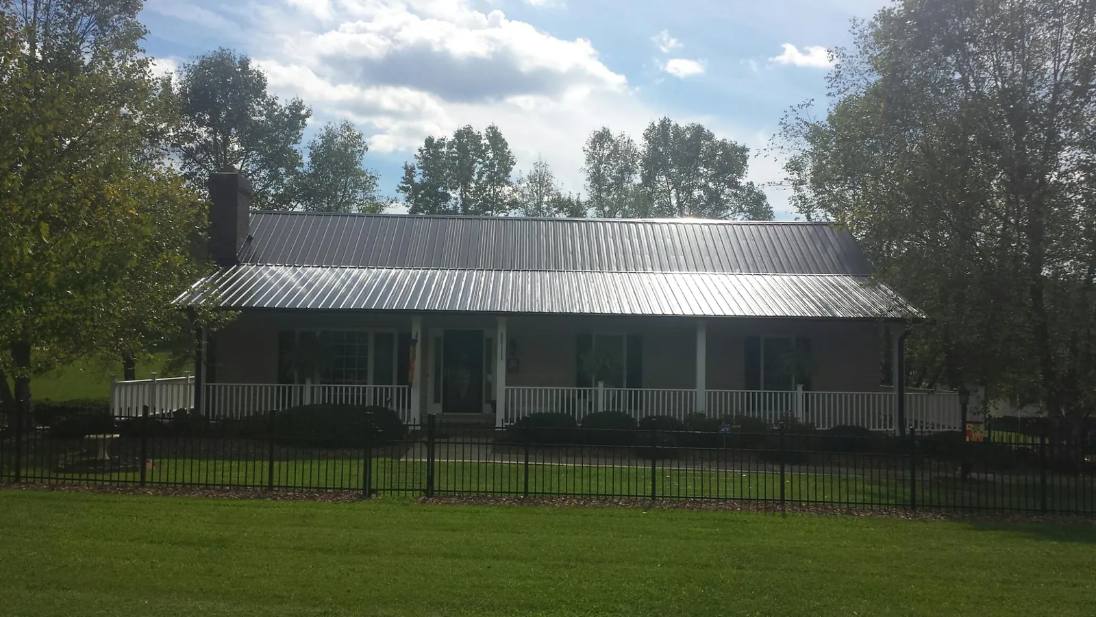 Gray metal roof on a brick ranch with a full width front porch — Gutter Guard Installation work by our crew in Vanleer