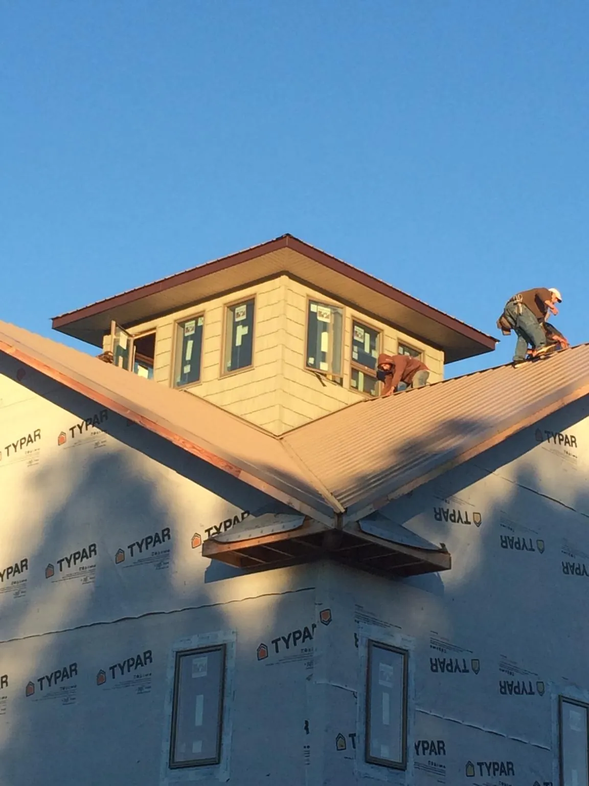 Roofers working around a rooftop cupola on a new metal roof at sunset — Roof Waterproofing in Vanleer by Roofing Brothers